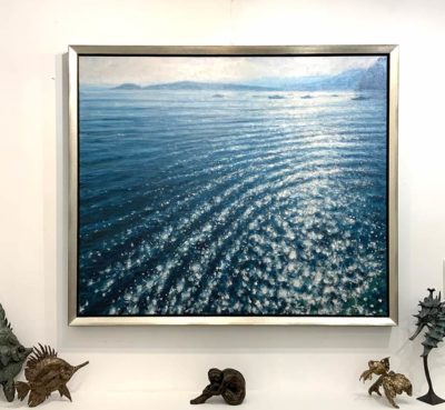 Justin Tew: Justin Tew at Norton Way Gallery Hertfordshire. This beautiful original, oil painting by Justin Tew depicts a sparkling ocean. The sun is reflected by the sea, in ripples across its surface. It is framed in a contemporary silver frame.