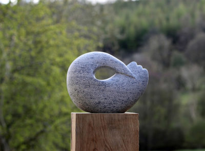 Jennifer Tetlow: This beautiful stone carving, sculpture by Jennifer Tetlow represents a lsymbolic sperically designed bird. Each piece of Jennifer Tetlow sculpture is individually carverd from, this one from an oolitic limestone.It is exhibited at Norton Way Gallery Hertfordshire. This piece is shown situated in a garden.
