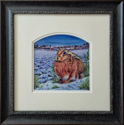 Collette Hoefkens at Norton Way Gallery, Hertfordshire. This original artwork by British artist, Collette Hoefkens, is an original artist's watercolour painting. It depicts a winter's brown Hare, sitting in a wintry landscape with snow.