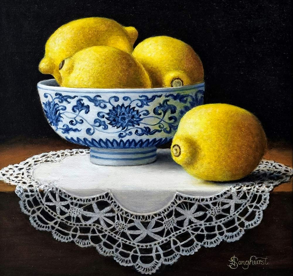 Anne Songhurst Art at Norton Way Gallery Hertfordshire. This beautiful oil painting is an original artwork by British artist Anne Songhurst. It is a still life painting, depicting four lemons, lace and a blue and white Chinese Bowl. It is framed in a dark wood frame.